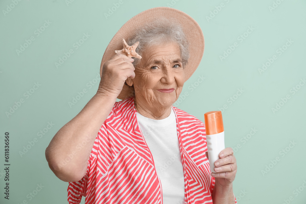 Senior woman with sunscreen cream and starfish on green background