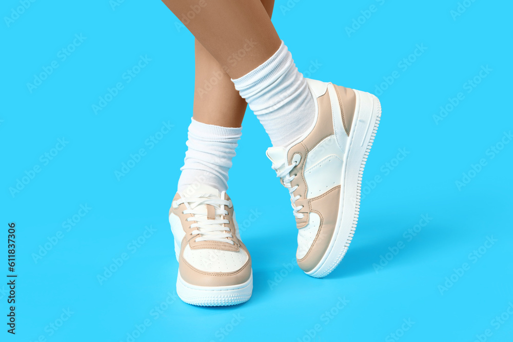 Female legs in stylish sneakers on color background, tights