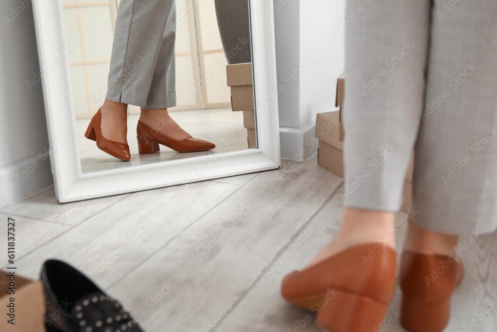 Woman trying on stylish high heeled shoes near mirror, closeup