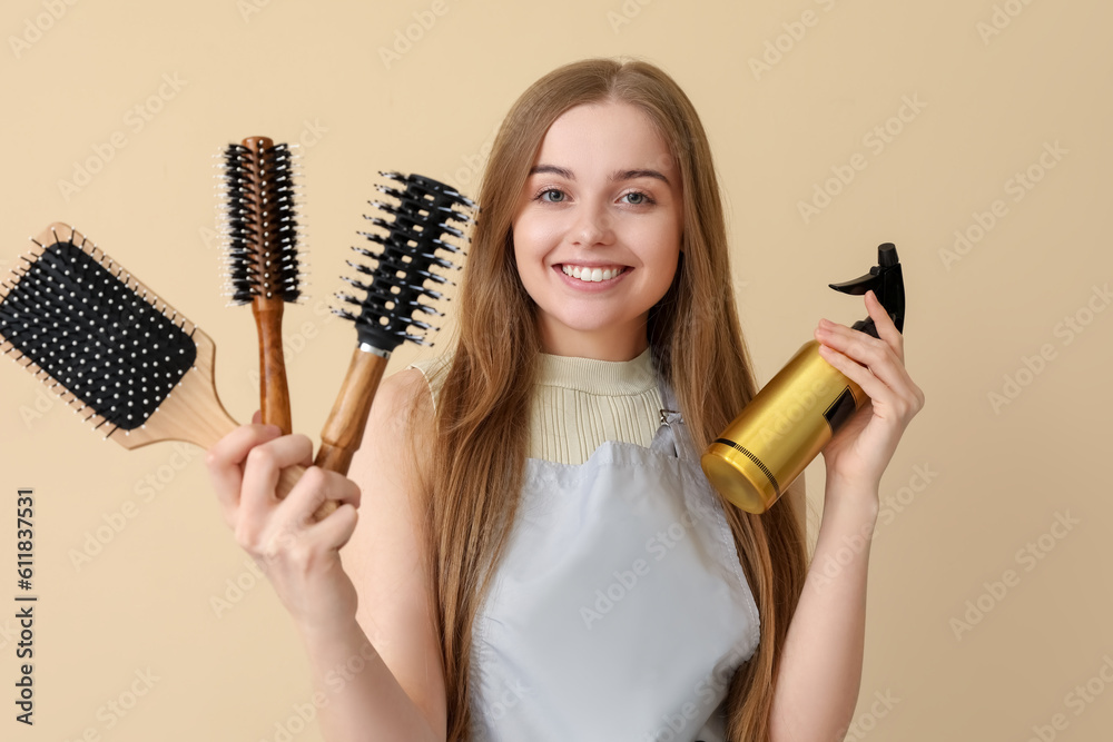 Female hairdresser with brushes and spray on beige background