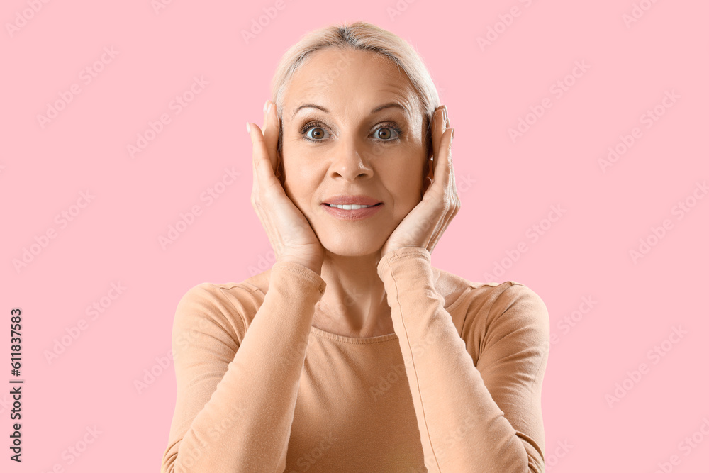 Mature woman doing face building exercise on pink background, closeup