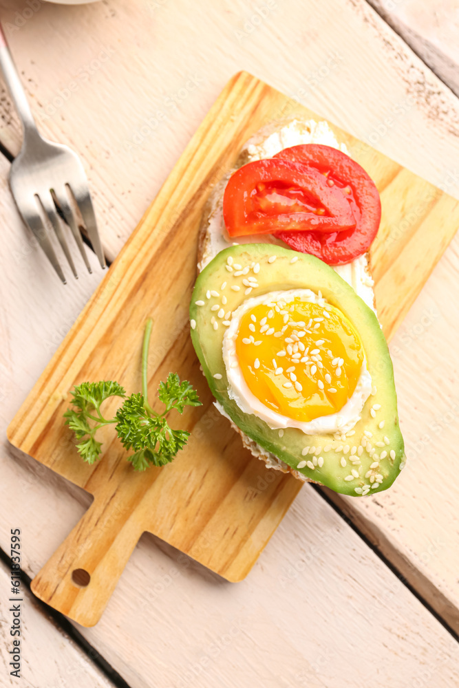 Board of tasty bruschetta with avocado and tomatoes on light wooden background