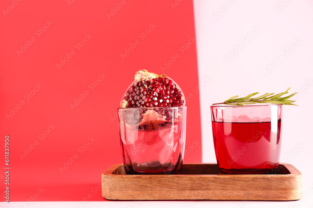 Board with glasses of fresh pomegranate juice on colorful background