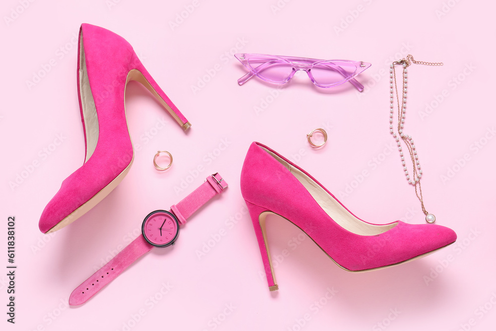 Sunglasses, pair of high heels, wristwatch and jewellery on pink background