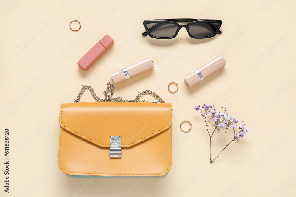 Sunglasses, purse, lipsticks, gypsophila flowers and jewellery on yellow background