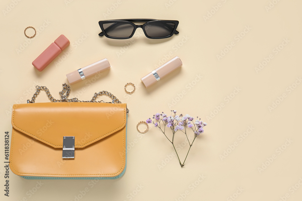 Sunglasses, purse, lipsticks, gypsophila flowers and jewellery on yellow background