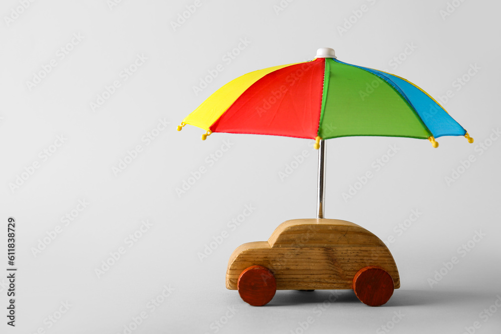 Creative composition with toy car and mini umbrella on white background. Insurance concept