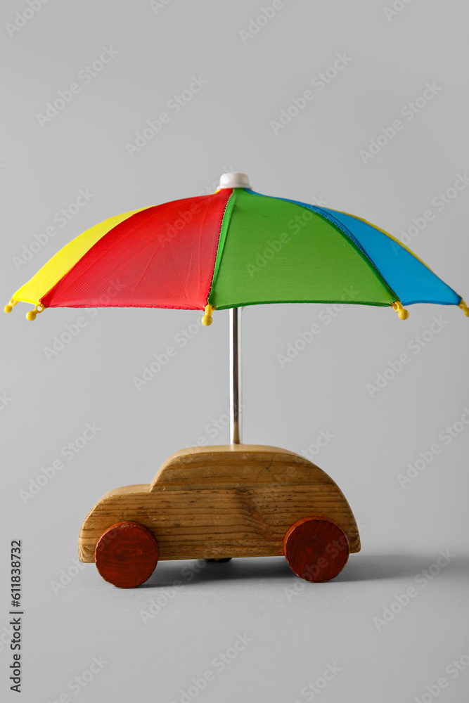 Creative composition with toy car and mini umbrella on white background. Insurance concept