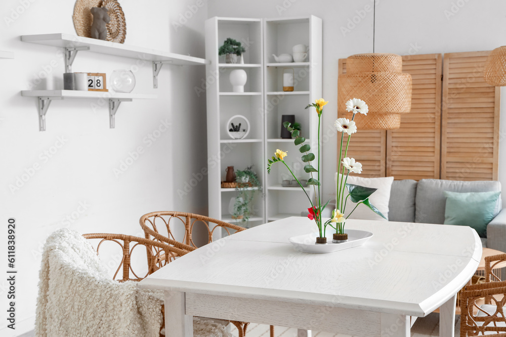 Beautiful ikebana on dining table in room