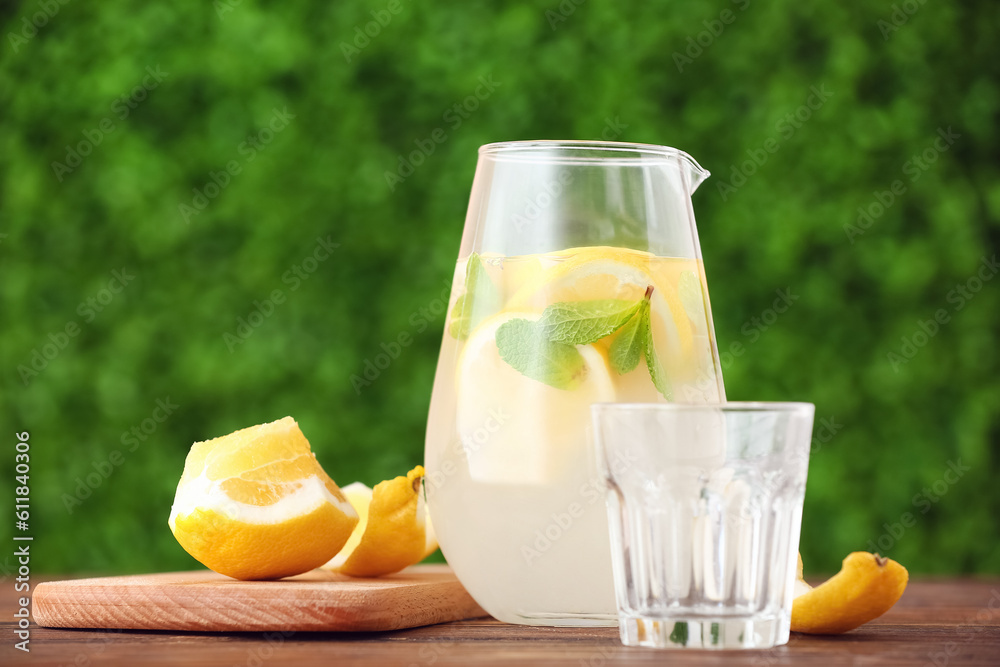 Jug and glass with fresh lemonade on wooden table