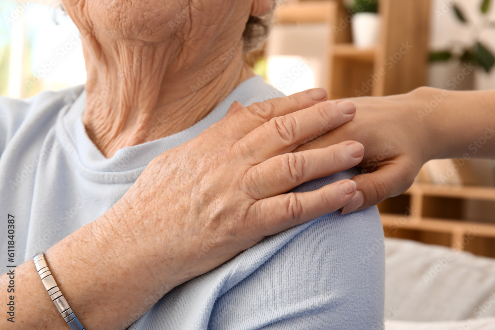 Senior woman with her granddaughter holding hands at home, closeup