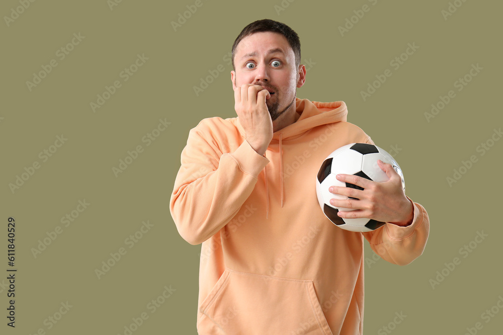 Scared man with soccer ball on color background