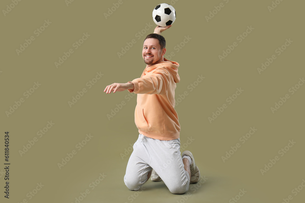 Happy man with soccer ball on color background