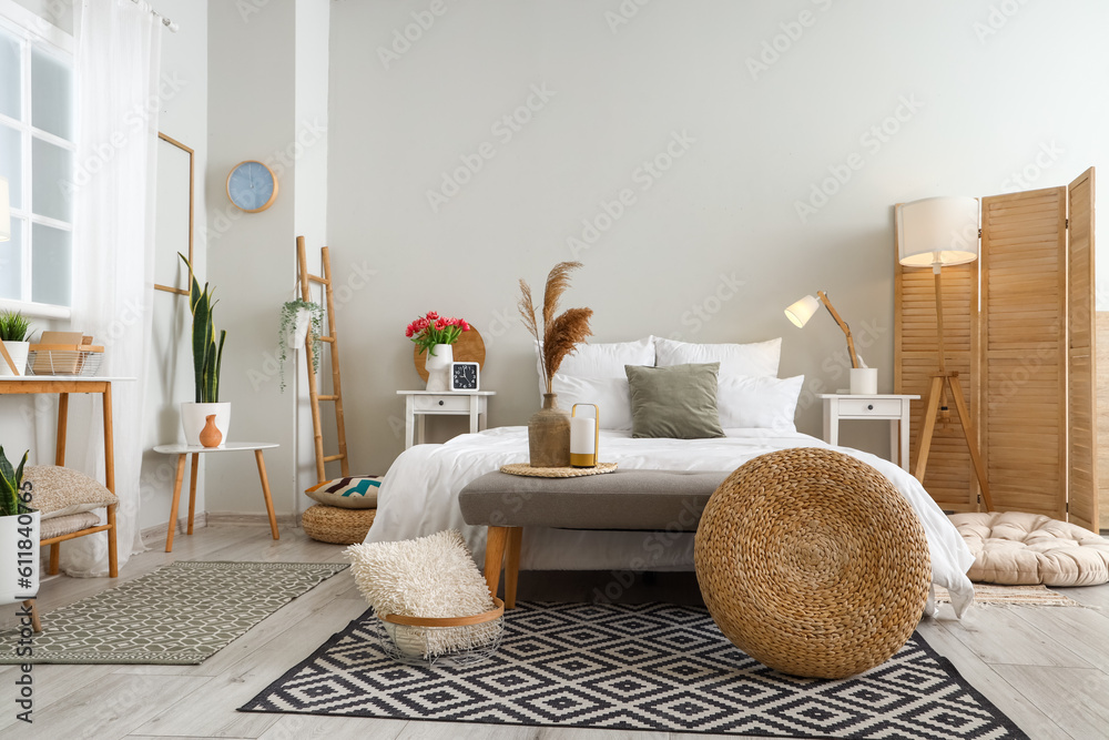 Interior of light bedroom with soft bench and tables