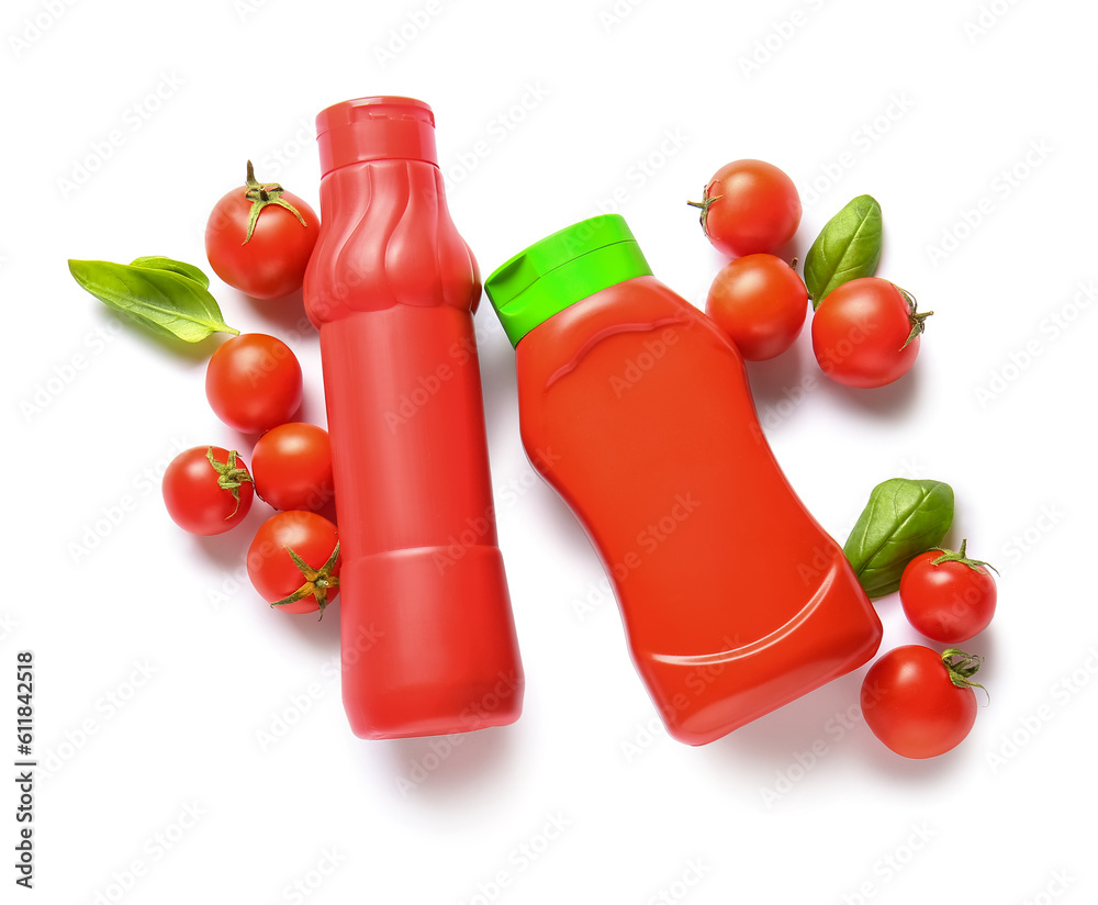 Bottles of ketchup and tomatoes on white background