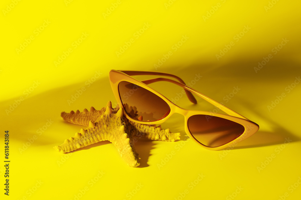 Stylish sunglasses with starfish on yellow background