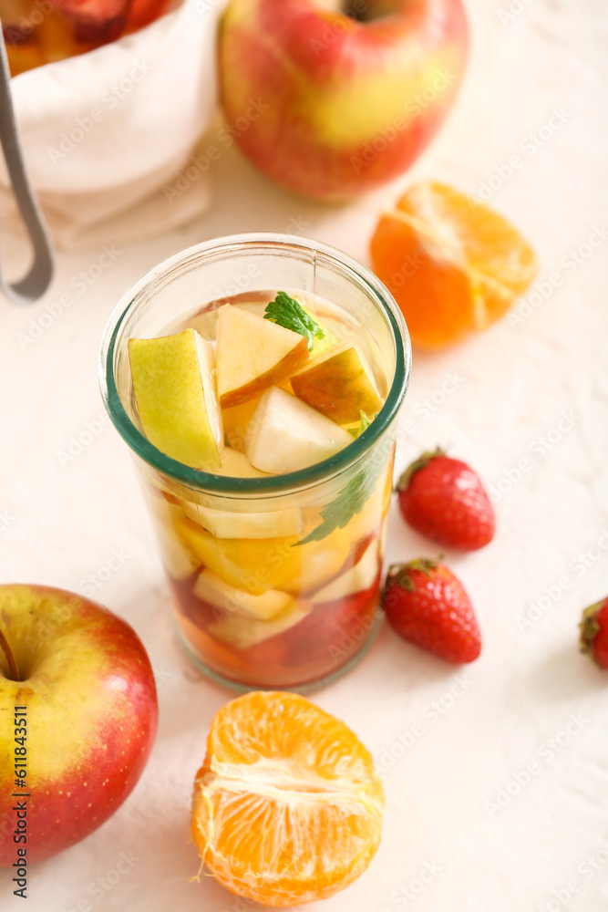 Glass of infused water with different sliced fruits on white table