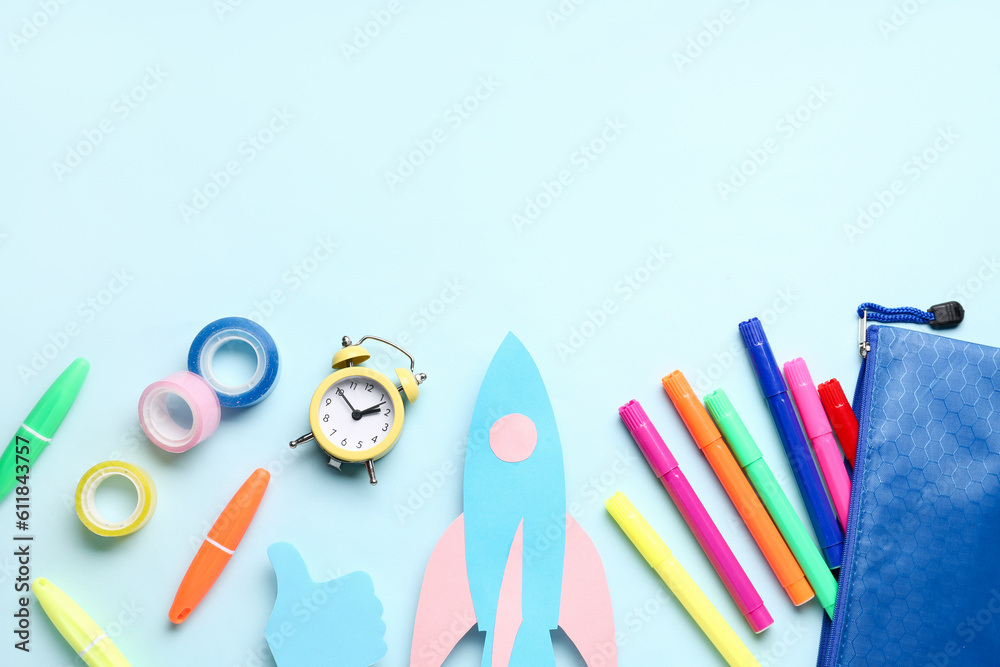 Paper rocket with pencil case and different stationery on blue background