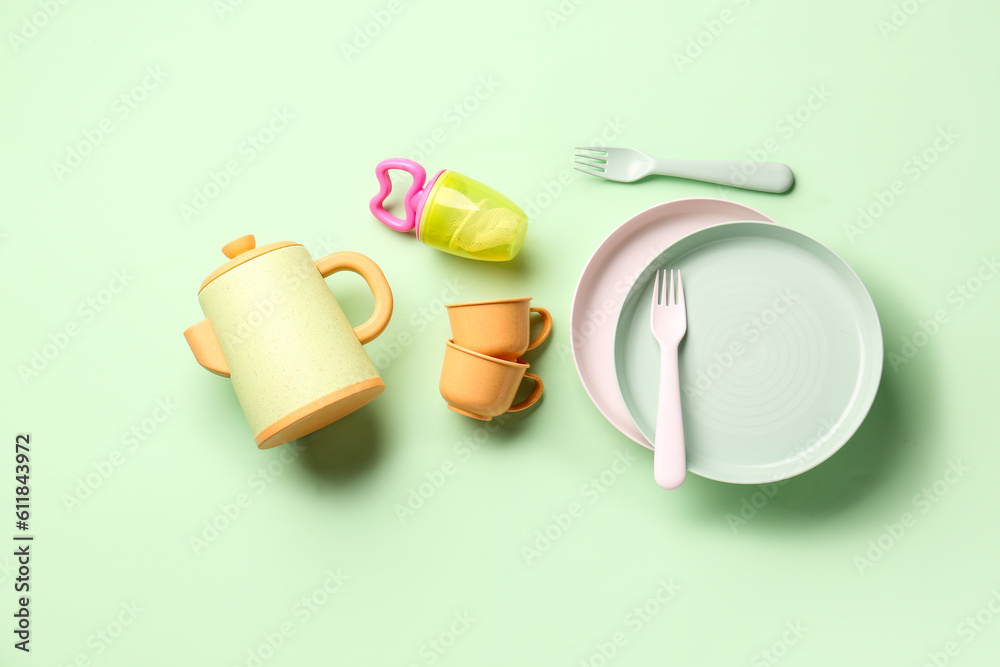 Different eating utensils for baby on pale green background