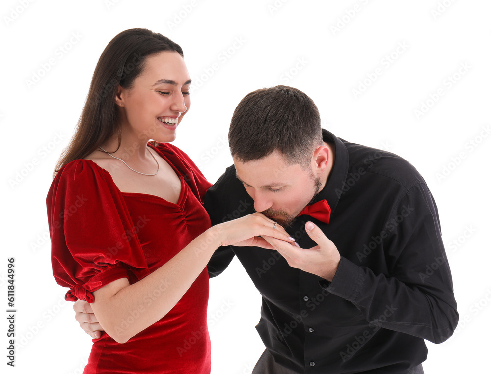 Young man kissing his girlfriends hand with engagement ring on white background