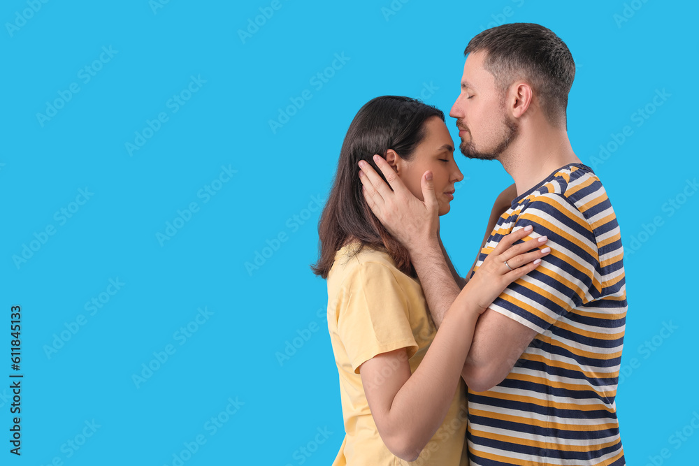 Happy engaged couple hugging on blue background