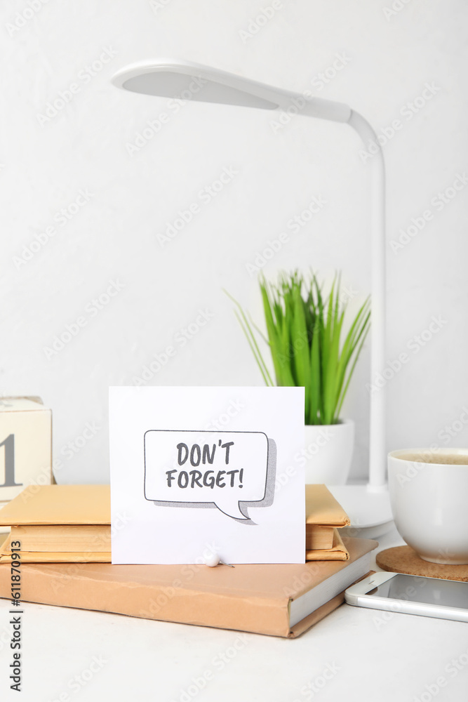 Dont forget reminder with books and mobile phone on white table