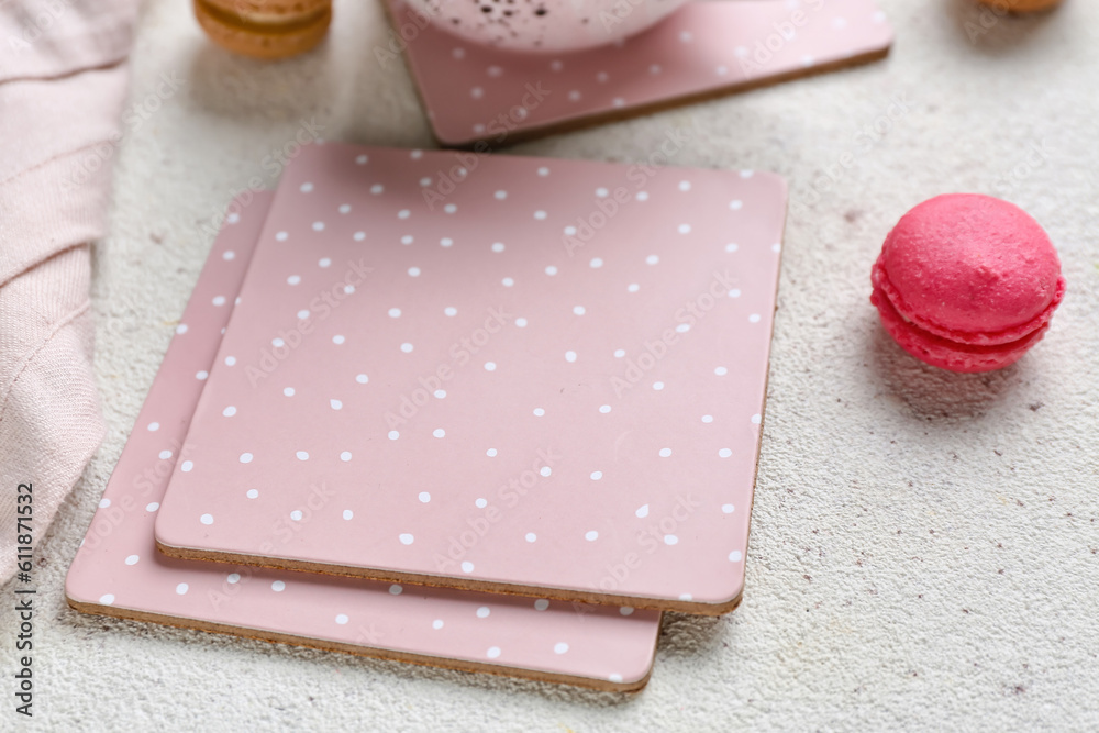 Pink drink coasters and macaroon on white table, closeup