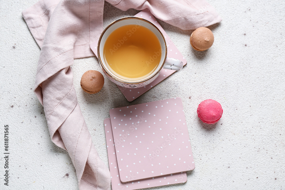 Drink coasters with cup of tea and macaroons on white table