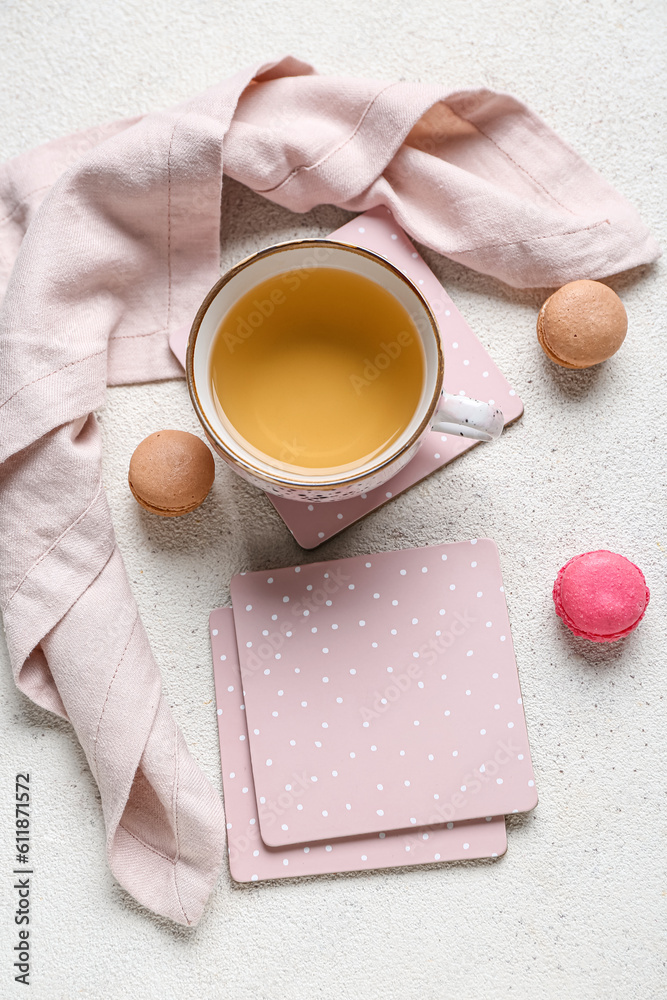 Drink coasters with cup of tea and macaroons on white table