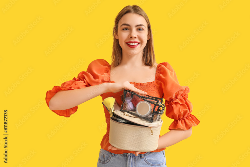 Young woman with cosmetic bags on yellow background