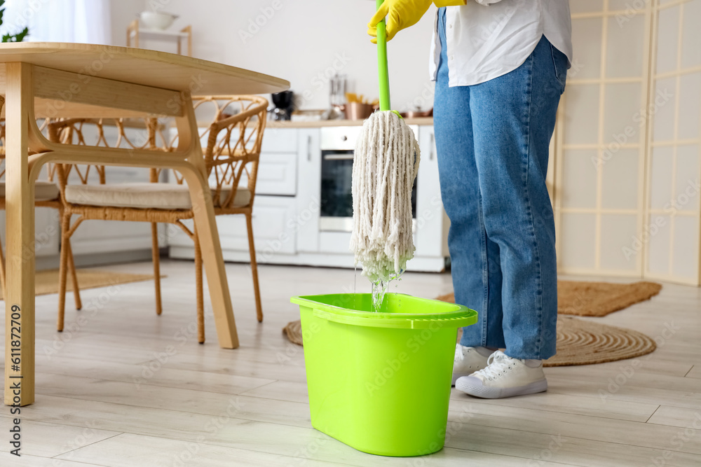 Housewife mopping floor in kitchen