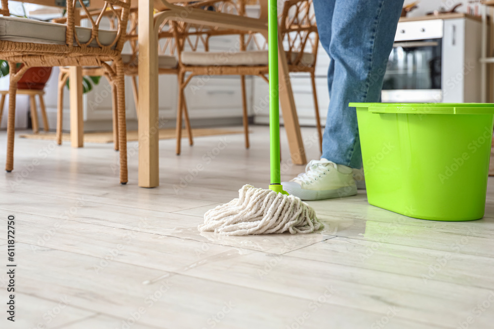 Housewife mopping floor in kitchen, closeup