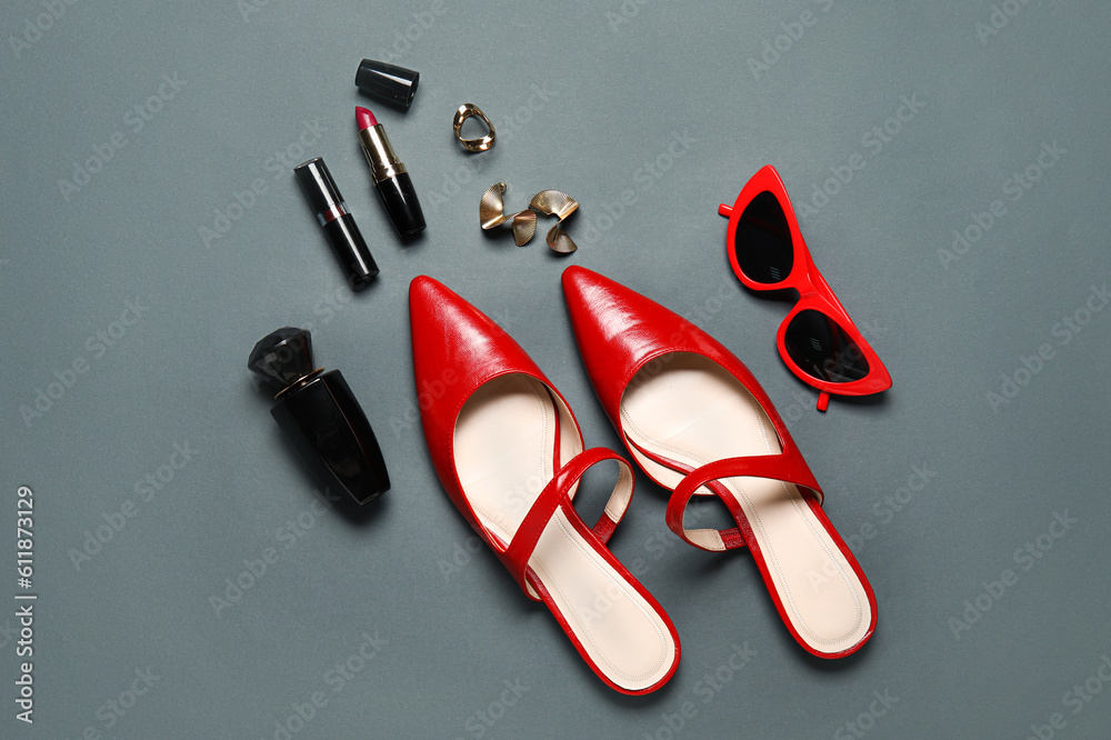 Stylish female shoes, cosmetics and accessories on dark background