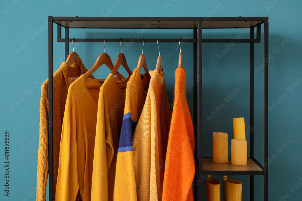 Shelving unit with clothes and candles near blue wall