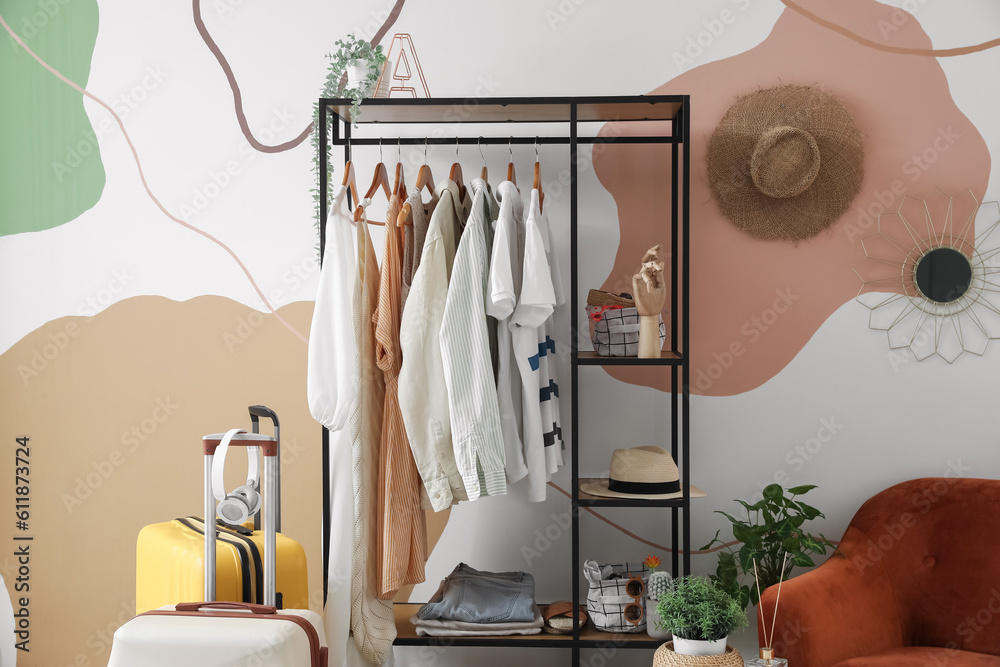 Shelving unit with clothes near color wall in room