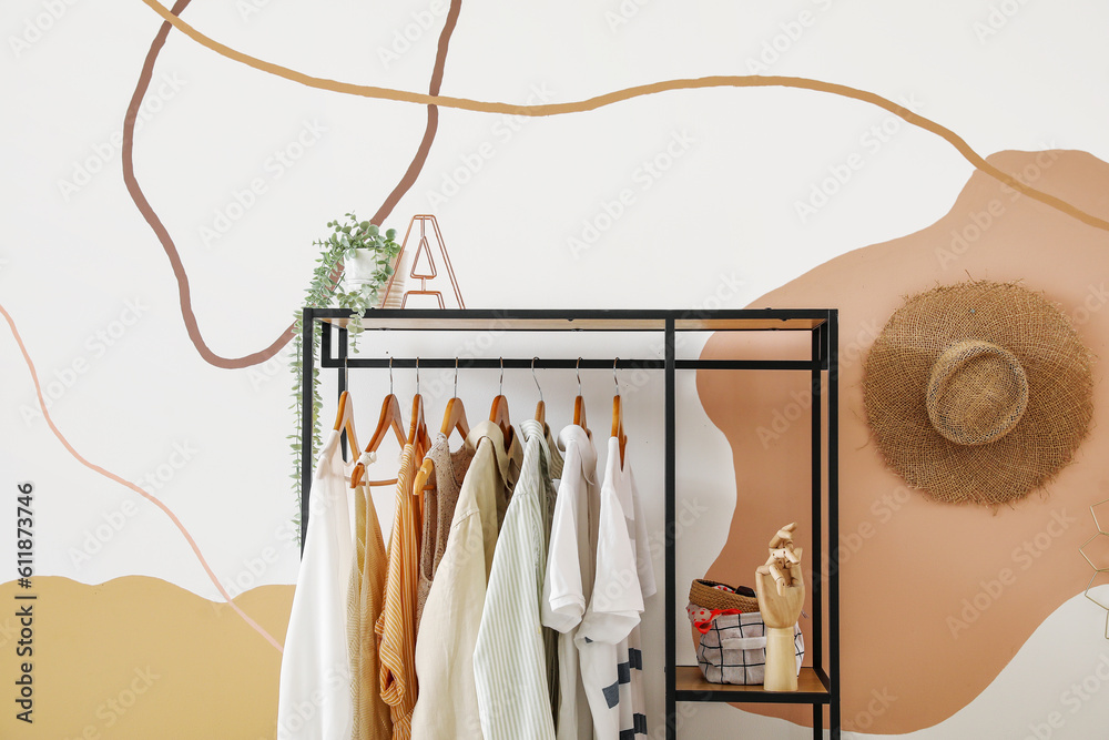 Shelving unit with clothes near color wall in room