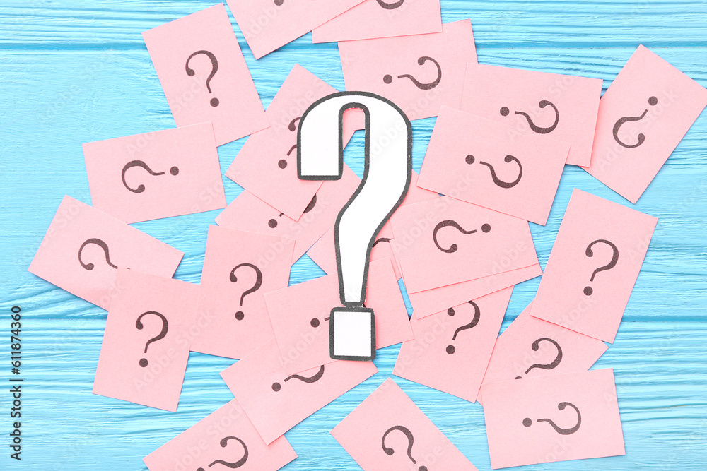 Papers with question marks on blue wooden background