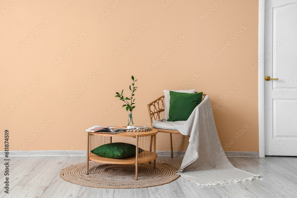 Armchair and coffee table with vase and magazines near beige wall