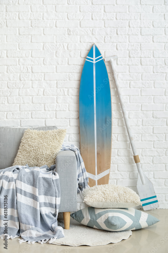 Interior of living room with surfboard, paddle and sofa