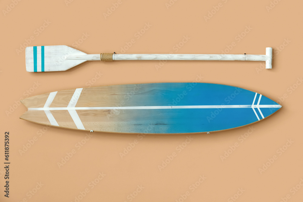 Wooden surfboard and paddle hanging on beige wall