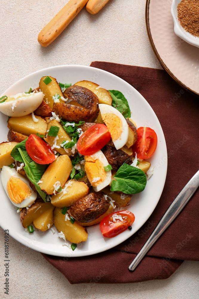 Plate of tasty potato salad with eggs and tomatoes on light background