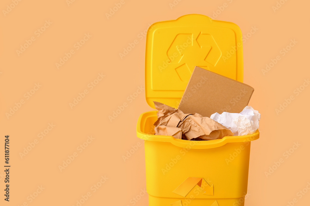 Container for garbage with paper on beige background. Recycling concept