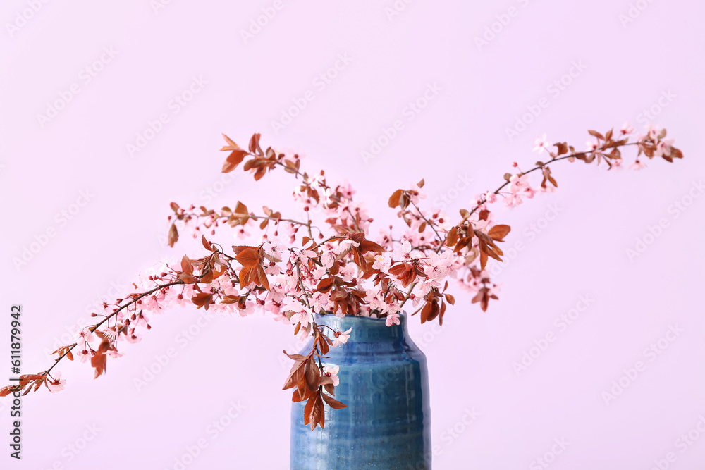 Vase with blooming tree branches on pink background