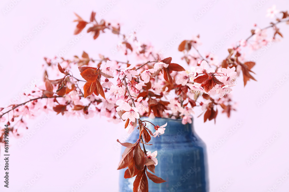 Vase with blooming tree branches on pink background