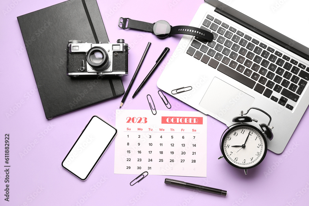 Composition with calendar, modern laptop, alarm clock, photo camera and mobile phone on lilac backgr