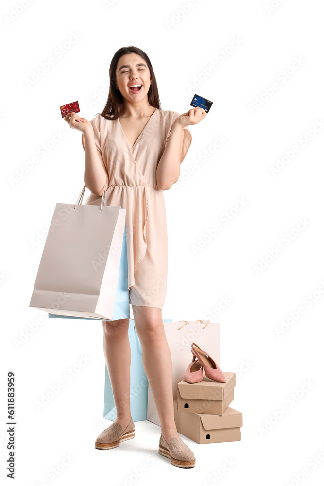 Young woman with credit cards and shopping bags on white background