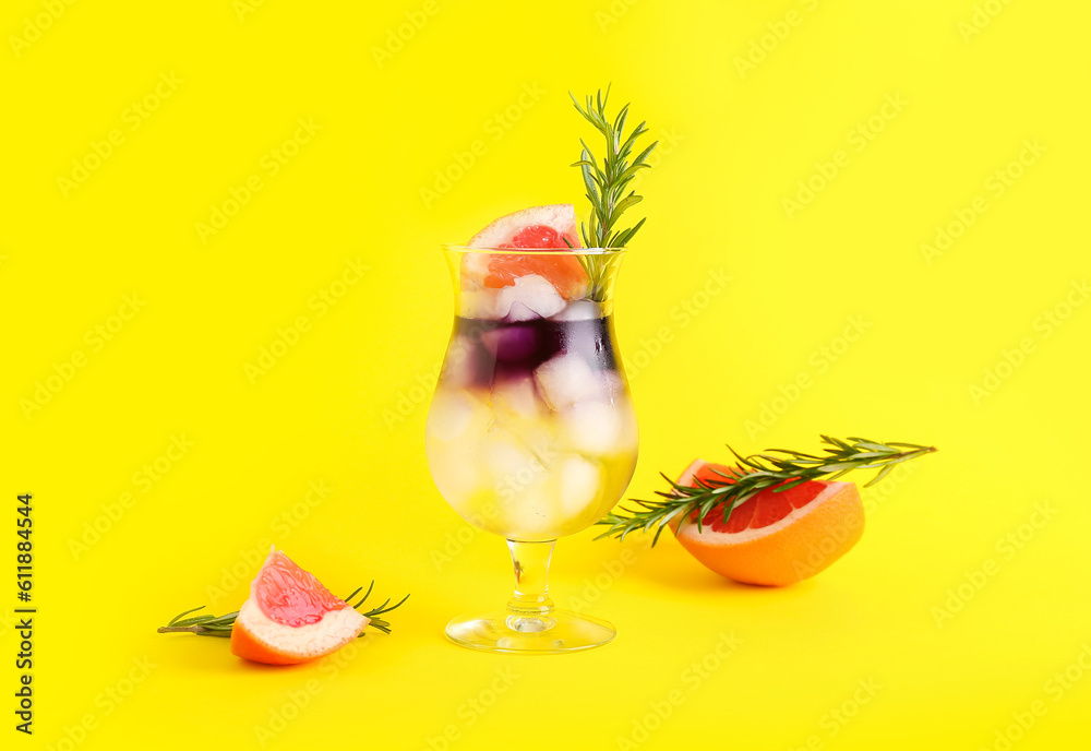 Glass of purple gin and tonic with grapefruit and rosemary on yellow background