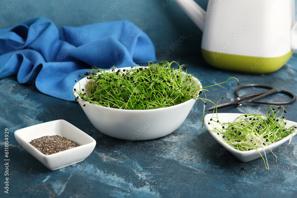 Bowls with fresh micro green and seeds on blue background