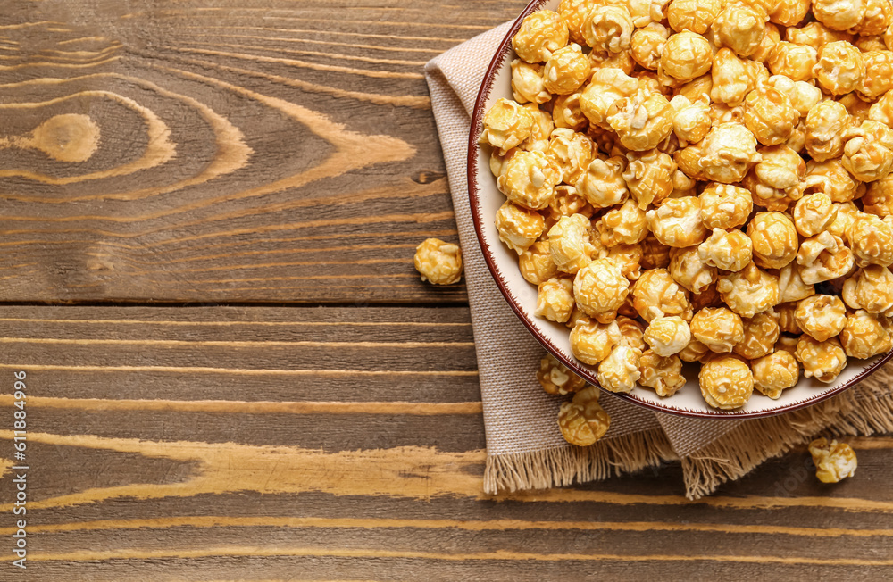 Bowl with crispy popcorn on wooden background