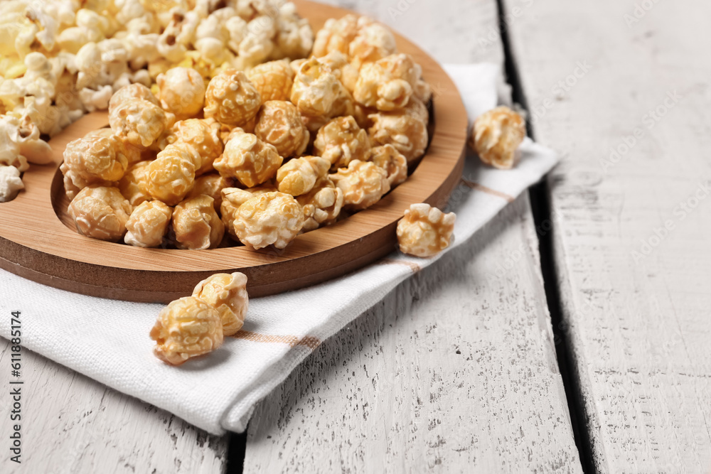 Plate with crispy popcorn on white wooden background